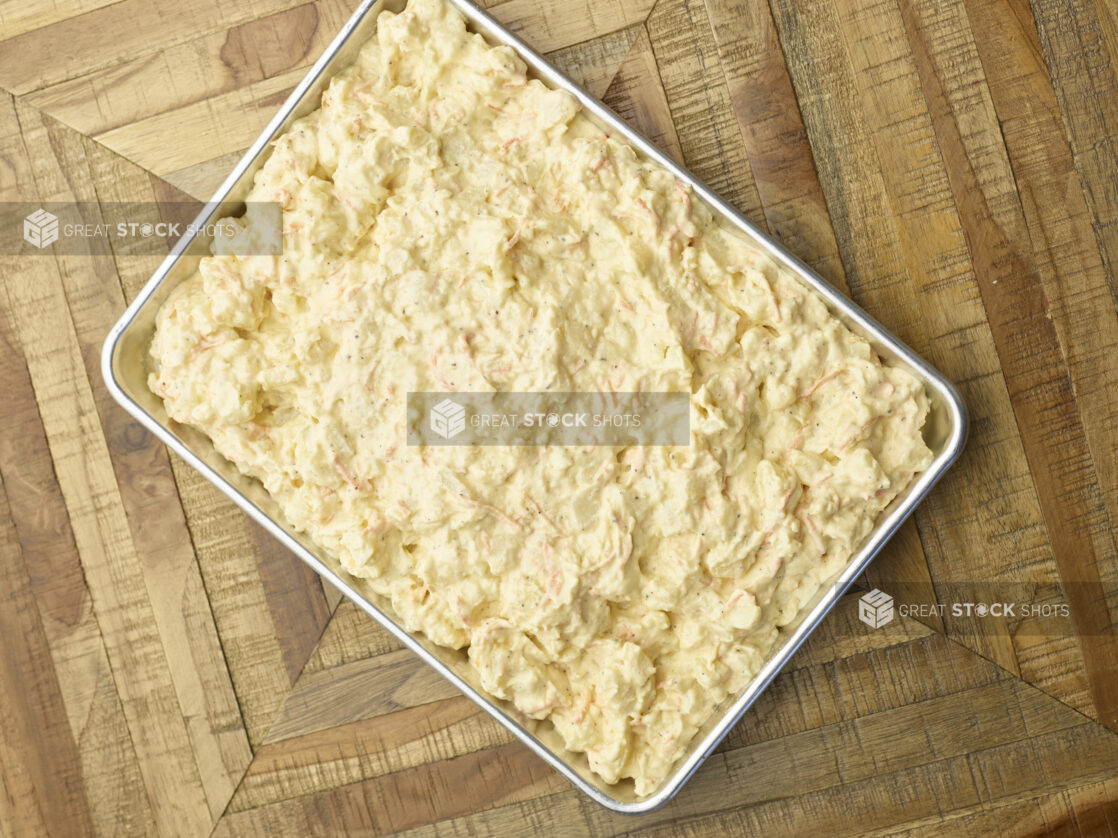 Overhead View of a Metal Baking Sheet Full of Prepared Potato Salad for Catering or a Party Tray, on a Wooden Parquet Floor