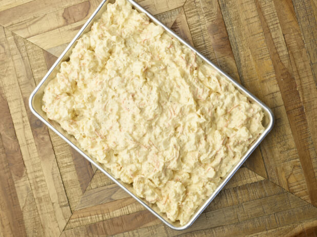 Overhead View of a Metal Baking Sheet Full of Prepared Potato Salad for Catering or a Party Tray, on a Wooden Parquet Floor