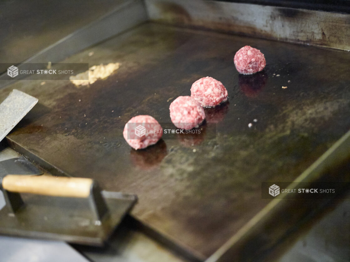 Ground Beef Meatballs Being Prepared to be Pressed on a Flat Top Grill to Cook Smash Burgers in a Gourmet Burger Restaurant