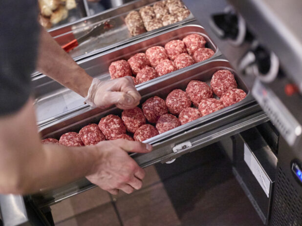 Chef's Hands Preparing Trays of Ground Beef Burger Patties Shaped into Balls for Grilling, in a Kitchen of a Gourmet Burger Restaurant