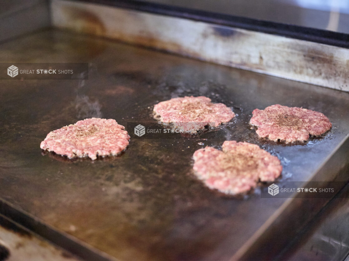 Smashed Beef Burger Patties Sizzling on a Flat Top Grill, in the Kitchen of a Gourmet Burger Restaurant