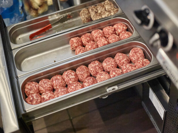 Trays of Ground Beef Burger Patties Shaped into Balls and Ready for Grilling, in a Kitchen of a Gourmet Burger Restaurant
