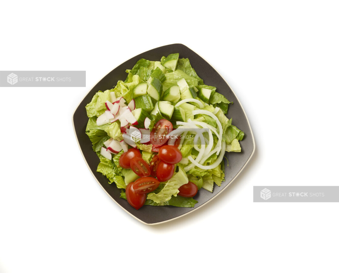 Overhead View of a Plain Garden Salad with Cherry Tomatoes, Cucumber, Radishes and White Onions on a Square Black Ceramic Dish, on a White Background for Isolation