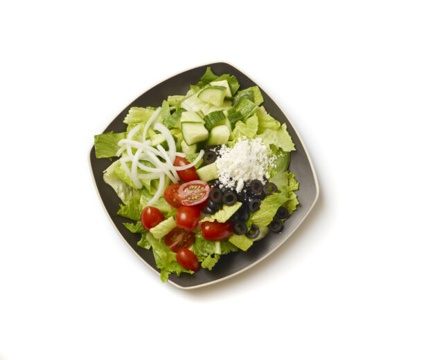 Overhead View of a Plain Greek Salad with Cherry Tomatoes, Cucumber, Black Olives, Feta and White Onions on a Square Black Ceramic Dish, on a White Background for Isolation