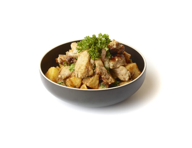 Garlic Potatoes and Chicken Shawarma Pieces Topped with Fresh Parsley Garnish in a Round Black Ceramic Bowl on a White Background for Isolation