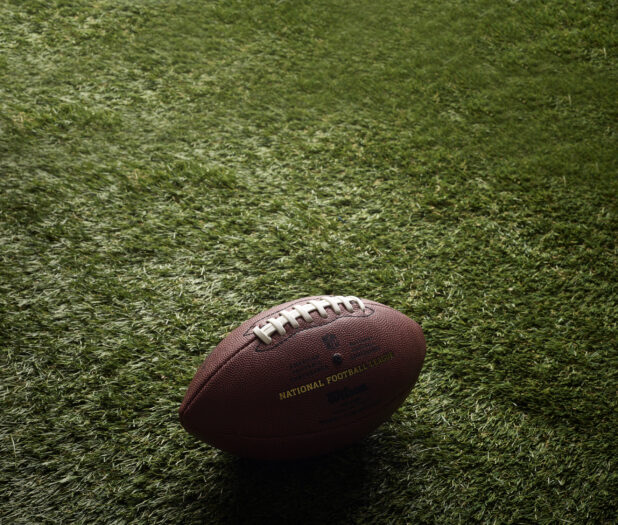 Close Up of an American Football on Astroturf in an Outdoor Setting