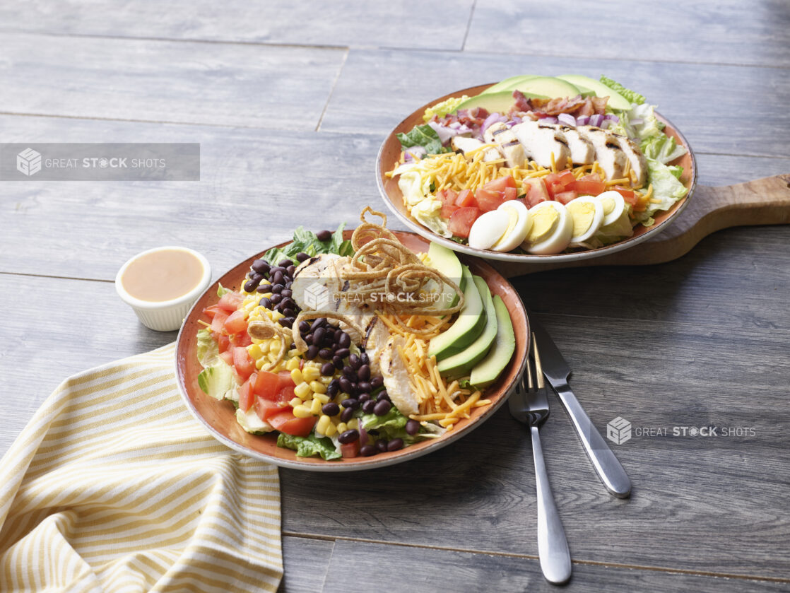 Two varieties of chopped salad on a grey tabletop