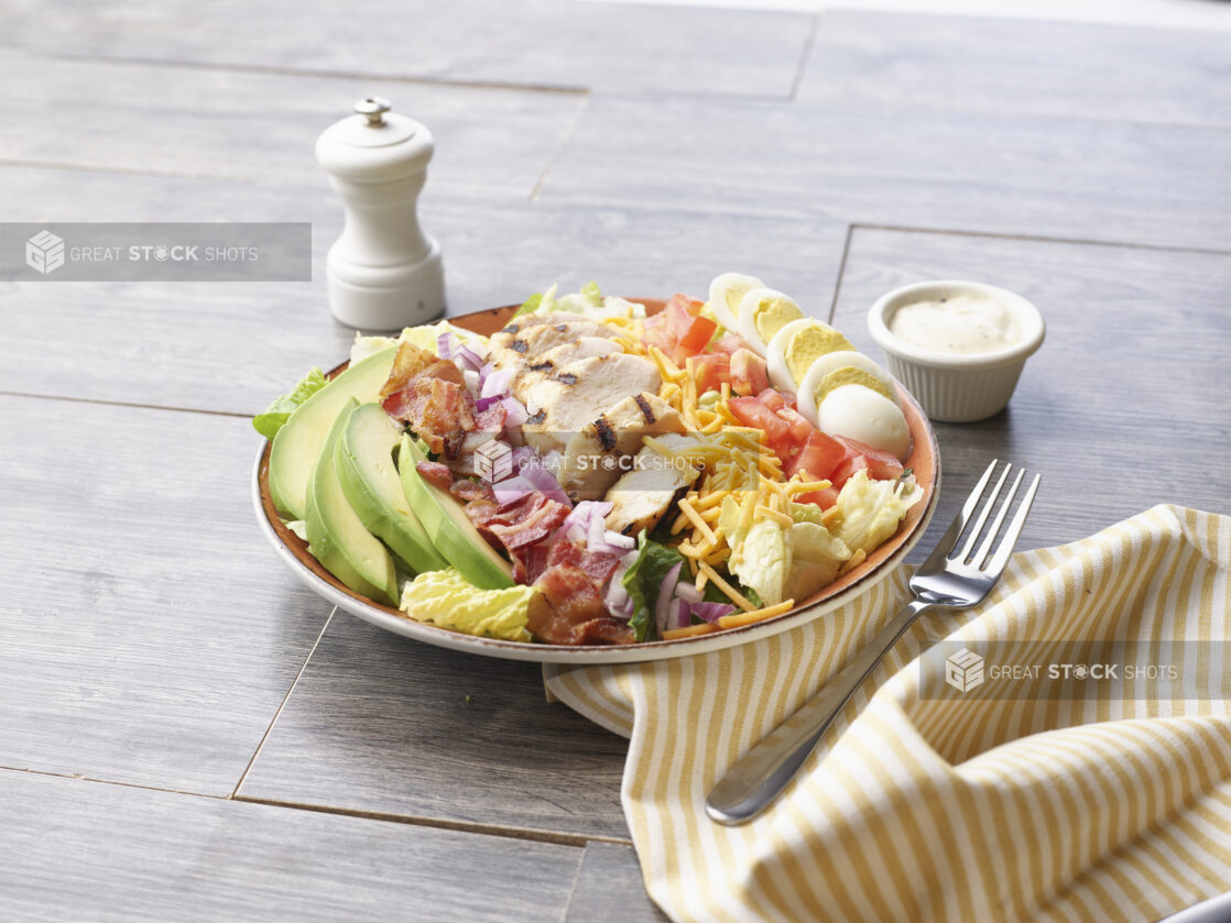 A Cobb salad in a ceramic Bowl on a wood background