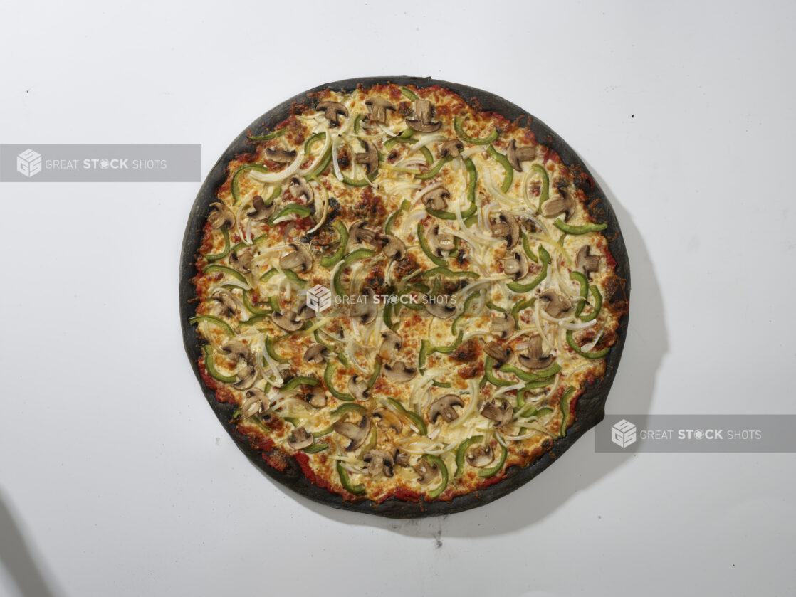 Overhead View of a Whole Charcoal-Infused Veggie Pizza with White Onions, Green Peppers and White Mushrooms Toppings, on a White Background for Isolation