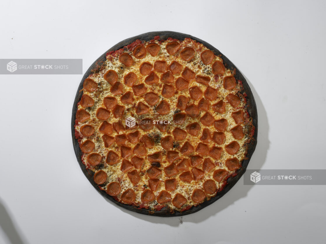 Overhead View of a Whole Charcoal-Infused Pizza with Pepperoni and Cheese, on a White Background for Isolation