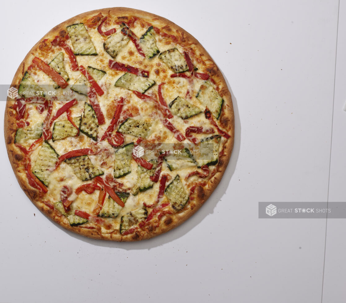 Overhead View of a Whole Specialty Pizza with Roasted Zucchini, Roasted Red Peppers, Parmesan Cheese Toppings, on a White Background for Isolation