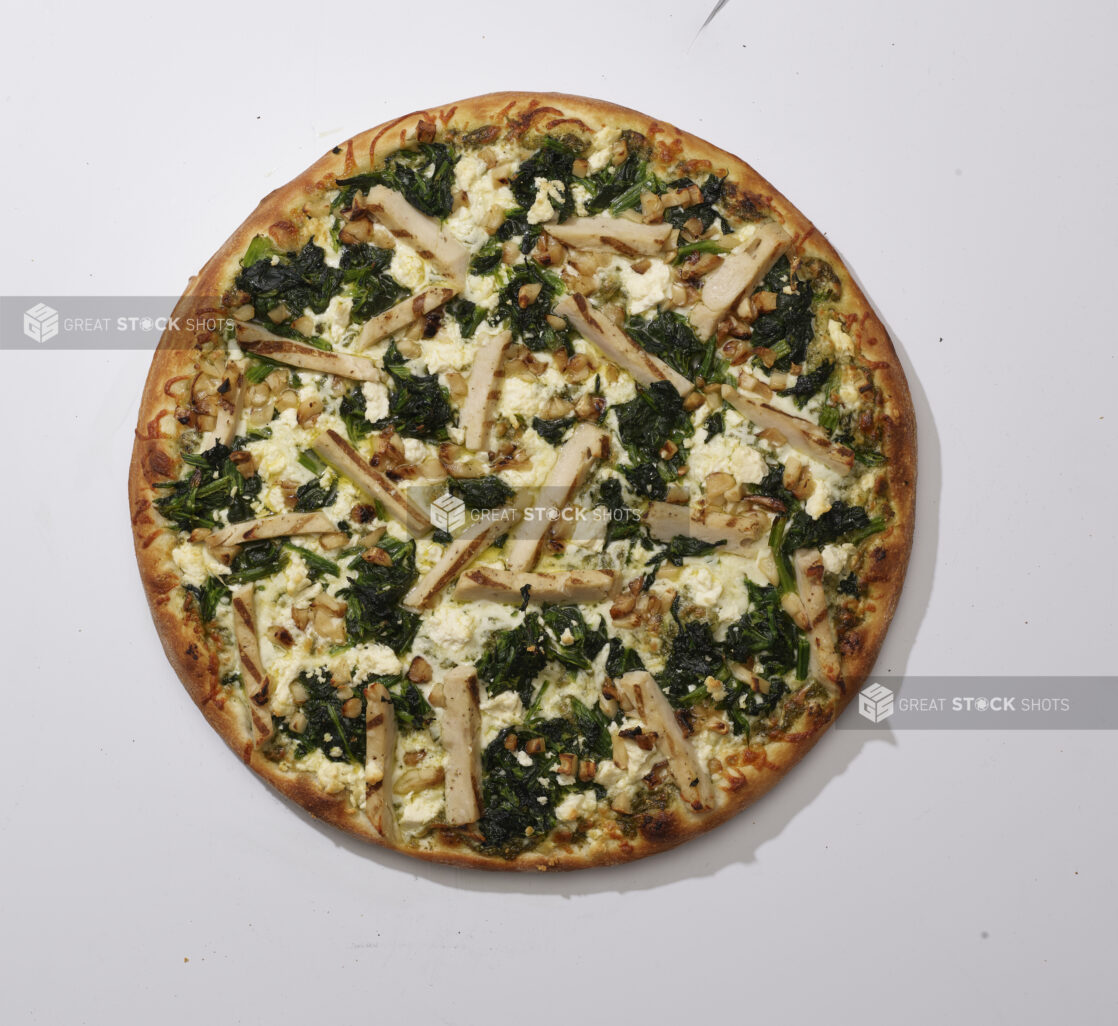 Overhead View of a Whole Chicken Florentine Pizza with Sautéed Spinach, Feta Cheese, Roasted Garlic and Grilled Chicken, on a White Background for Isolation