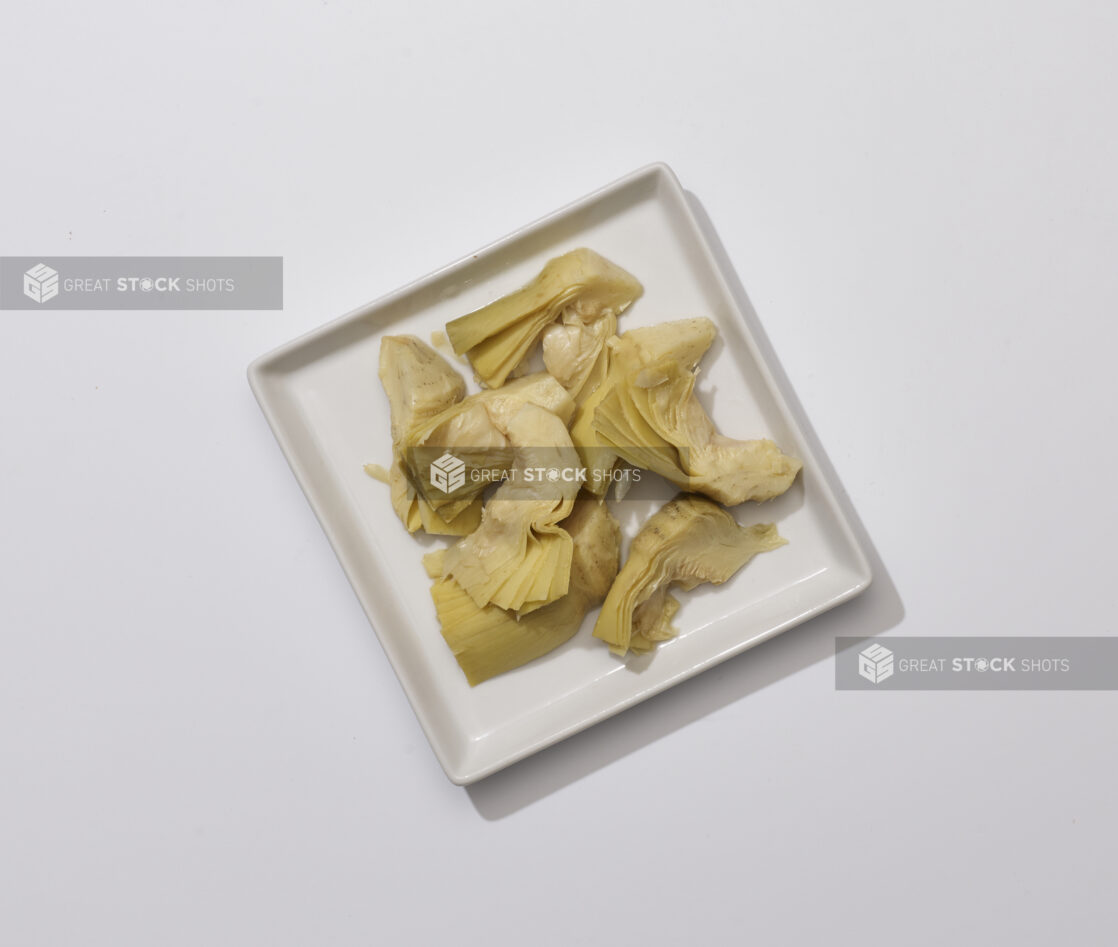 Overhead View of Pickled Artichoke Hearts a Square White Ceramic Dish, on a White Background for Isolation