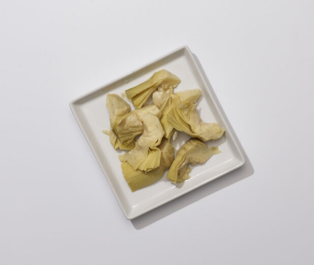 Overhead View of Pickled Artichoke Hearts a Square White Ceramic Dish, on a White Background for Isolation