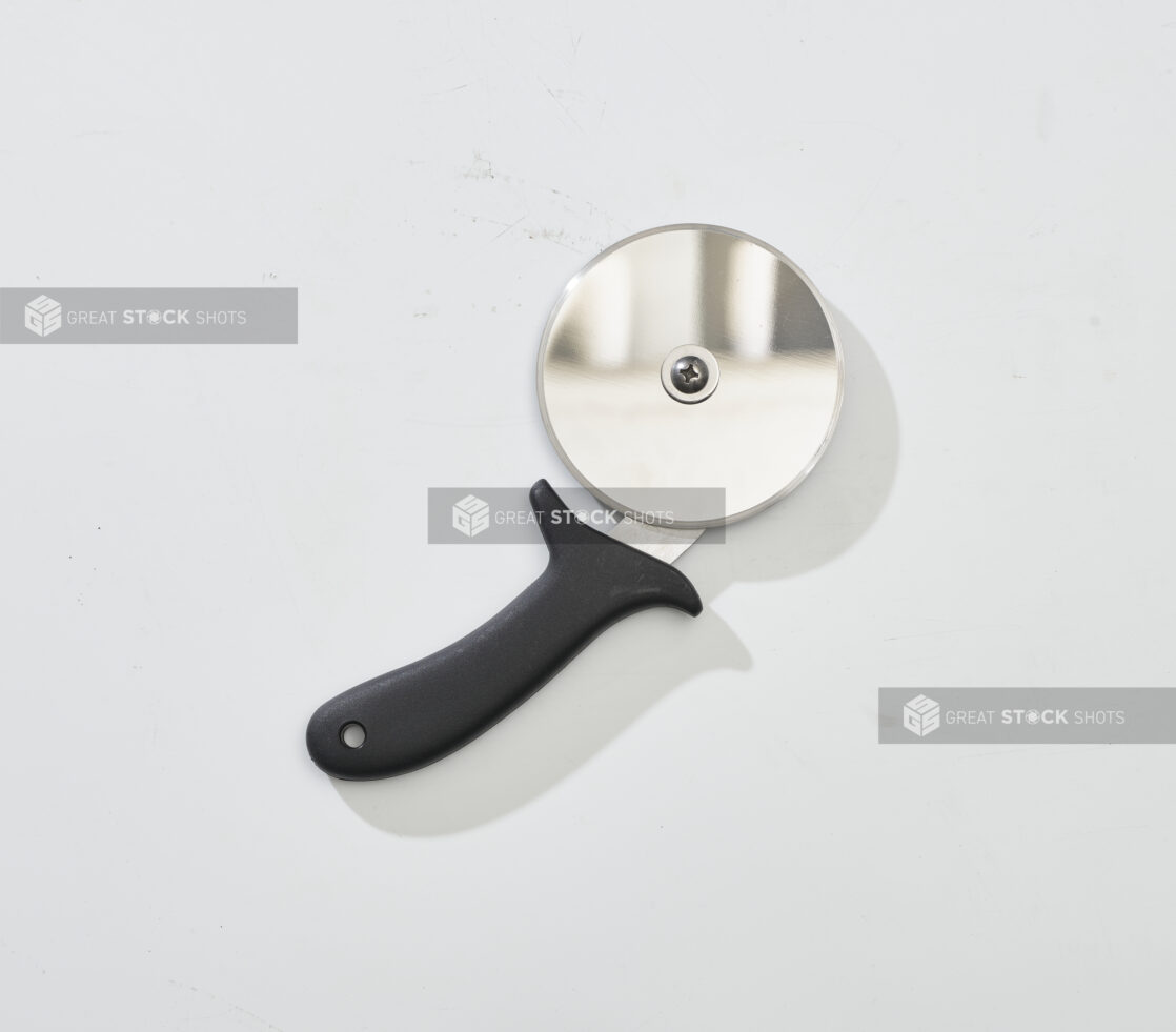 Overhead View of a Pizza Cutter with a Black Handle, on a White Background for Isolation