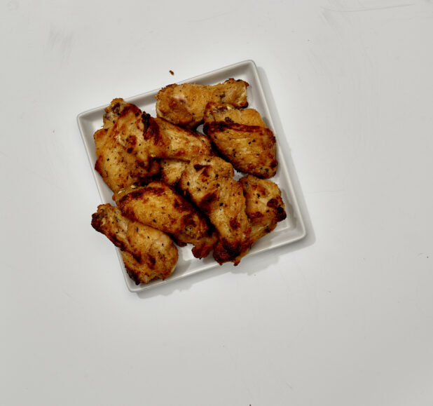 Overhead View of Roasted Italian Herb Chicken Wings on a Square White Ceramic Dish, on a White Background for Isolation