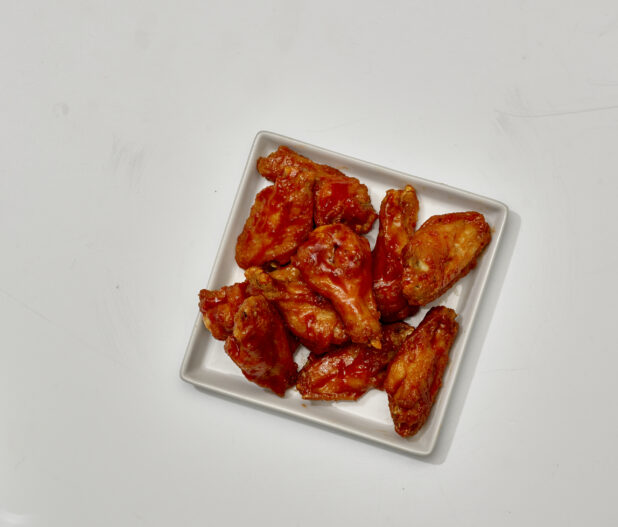 Overhead View of Sauced Chicken Wings on a Square White Ceramic Dish, on a White Background for Isolation