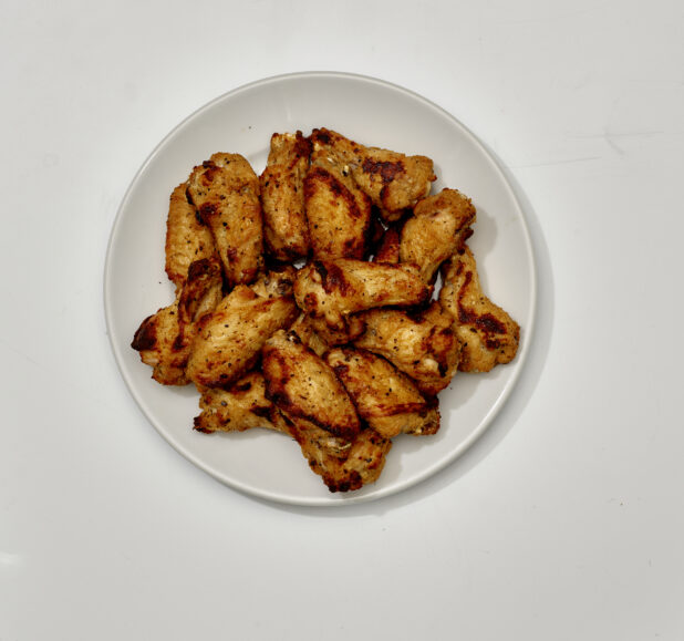 Overhead View of a Large Order of Roasted Italian Herb Chicken Wings on a Round White Ceramic Dish, on a White Background for Isolation