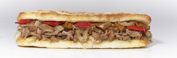An Italian Porchetta Sandwich with Hot Peppers and Sautéed Onions on Ciabatta Bread, on a White Background for Isolation