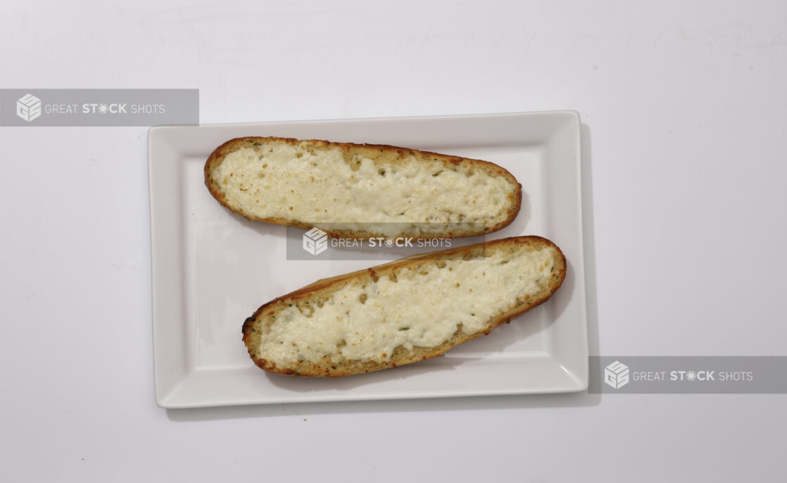 Overhead View of Garlic Bread on Mini Baguette Halves with Melted Vegan Cheese on a Rectangular White Platter, on a White Background for Isolation