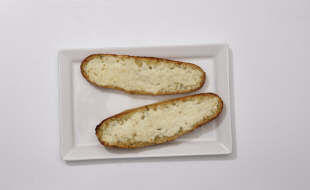 Overhead View of Garlic Bread on Mini Baguette Halves with Melted Vegan Cheese on a Rectangular White Platter, on a White Background for Isolation
