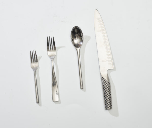 Overhead View of Stainless Steel Cutlery and an Engineered Steel Kitchen Knife, on a White Background for Isolation