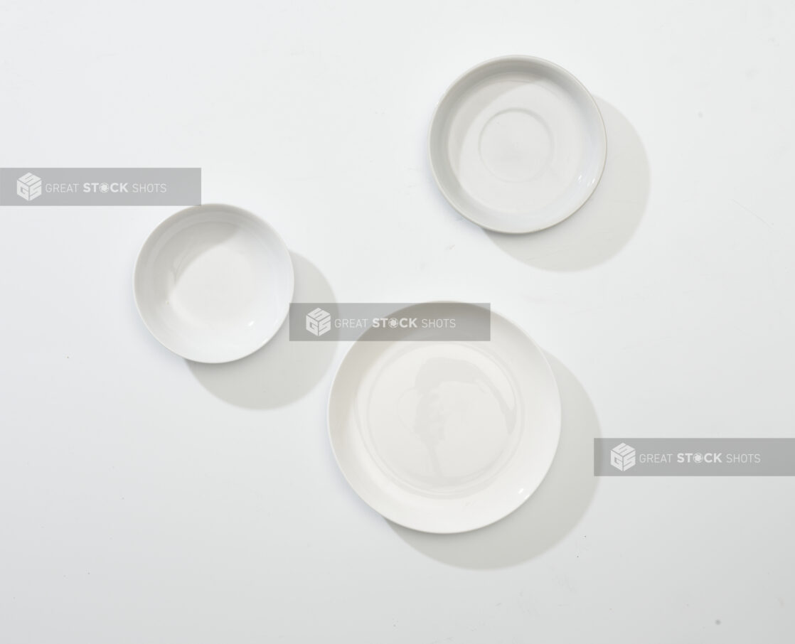 Overhead View of a Trio of White Round Ceramic Dishes, Plates and Bowls, on a White Background for Isolation