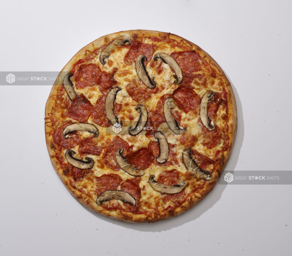 Overhead View of a Whole Specialty Pizza with Spicy Soppressata Salami and Portobello Mushroom Toppings, on a White Background for Isolation