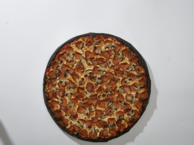 Overhead View of a Whole Charcoal-Infused Canadian Pizza with Pepperoni, Bacon and White Mushrooms Toppings, on a White Background for Isolation