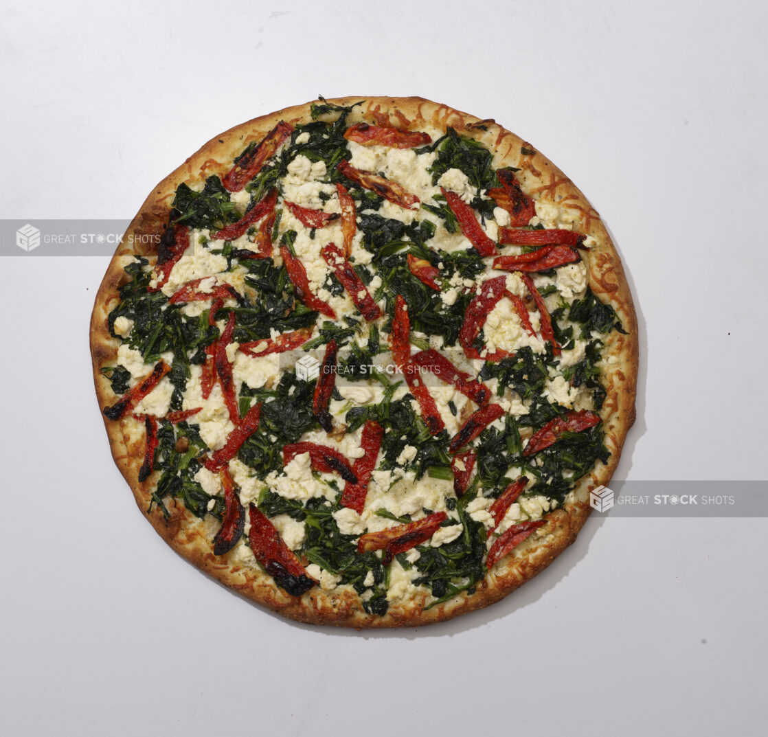 Overhead View of a Whole Pizza with Sautéed Spinach, Roasted Red Peppers and Feta Cheese, on a White Background for Isolation