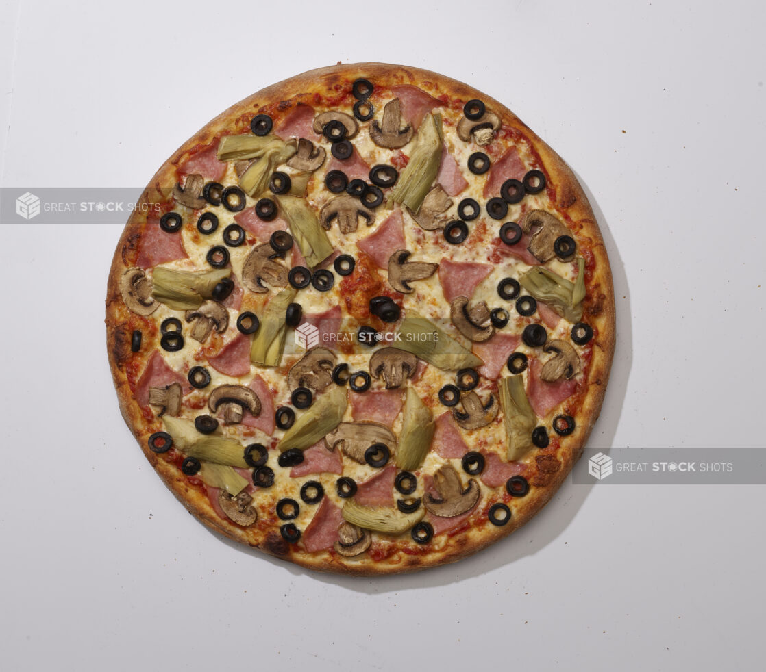 Overhead View of a Whole Specialty Pizza with Ham, Artichoke Hearts, White Mushrooms and Black Olives Toppings, on a White Background for Isolation