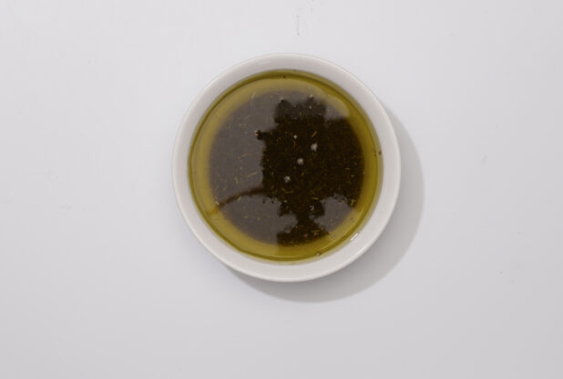 Overhead View of a Small Round Ceramic Bowl of Extra Virgin Olive Oil and Italian Herbs, on a White Background for Isolation