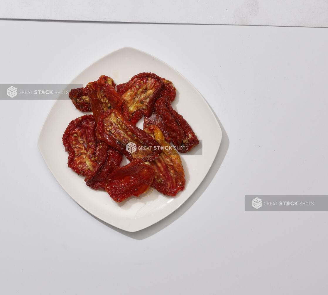 Overhead View of Sun-dried Tomato Slices on a Square White Ceramic Dish, on a White Background for Isolation