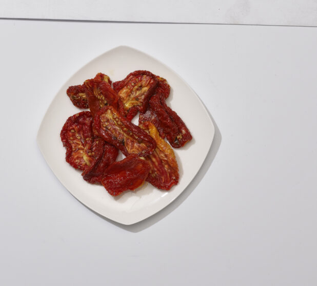 Overhead View of Sun-dried Tomato Slices on a Square White Ceramic Dish, on a White Background for Isolation