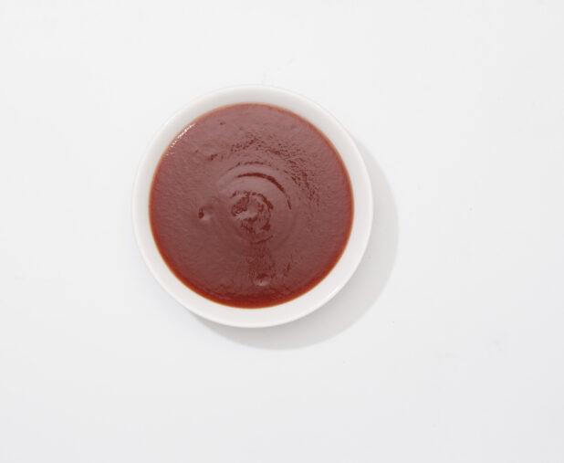 Overhead View of a Small Round Ceramic Bowl of BBQ Sauce, on a White Background for Isolation