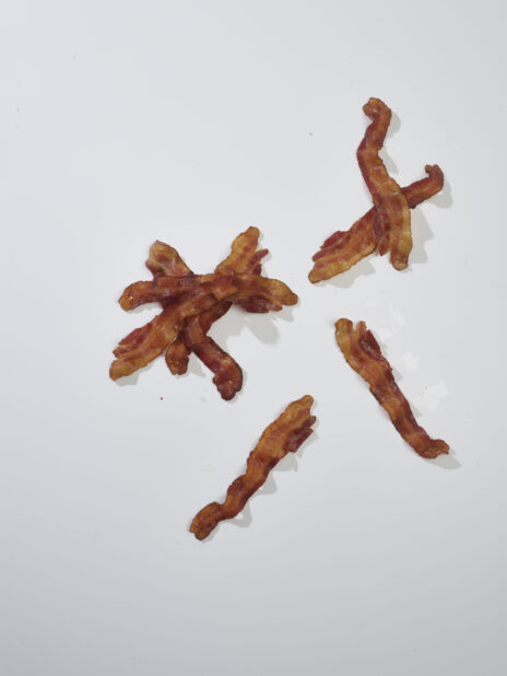 Cooked side bacon strips on a white background