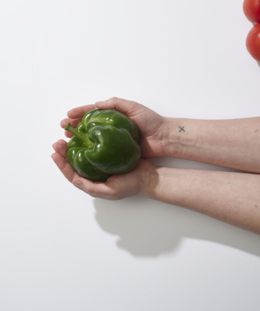 Hands holding a green bell pepper