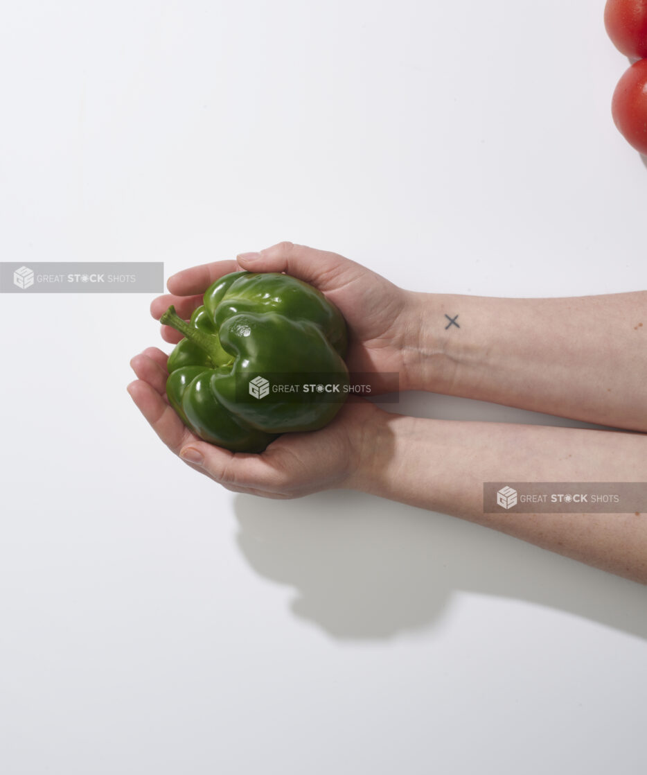 Hands holding a green bell pepper