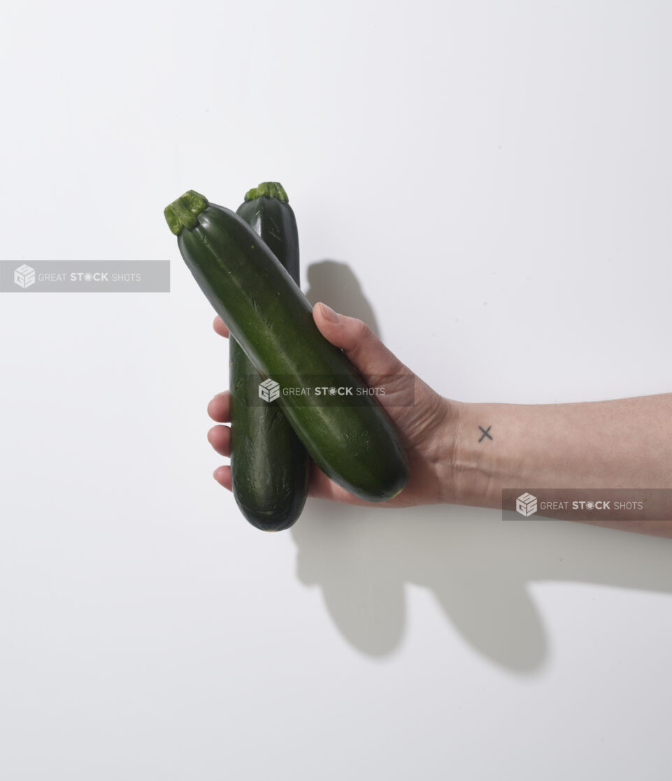 Hand holding fresh zucchini on a white background