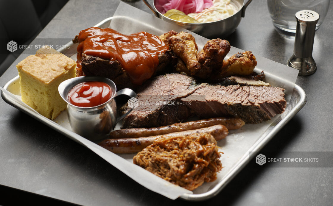 An assorted platter of meats with cornbread at a restaurant table