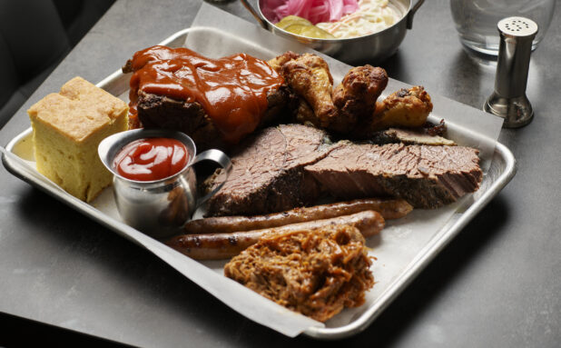 An assorted platter of meats with cornbread at a restaurant table