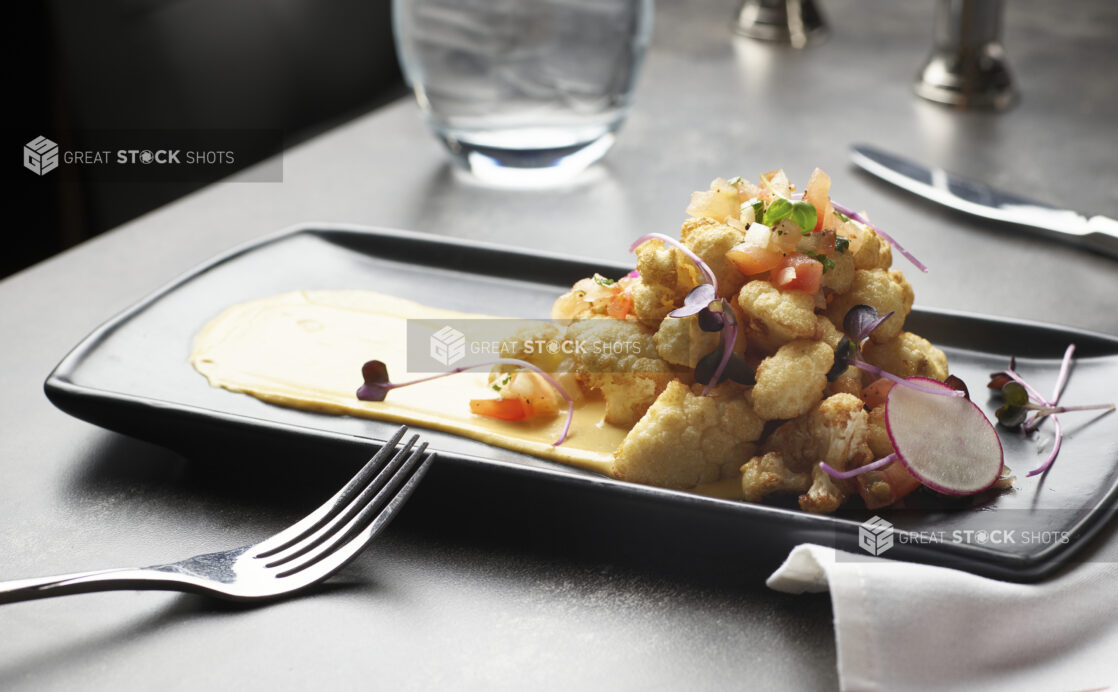 Roasted cauliflower with red pepper hummus and microgreen garnish