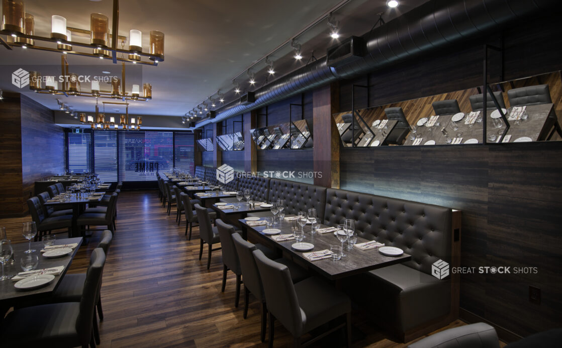 An elegant restaurant floor with dark upholstery, modern chandeliers and mirrors on the wall