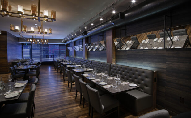 An elegant restaurant floor with dark upholstery, modern chandeliers and mirrors on the wall