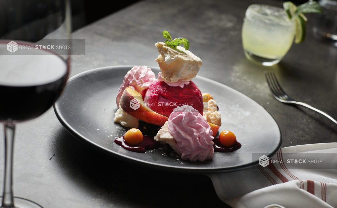 A fruit sorbet dessert with fresh fruit whipped cream and a fresh mint garnish