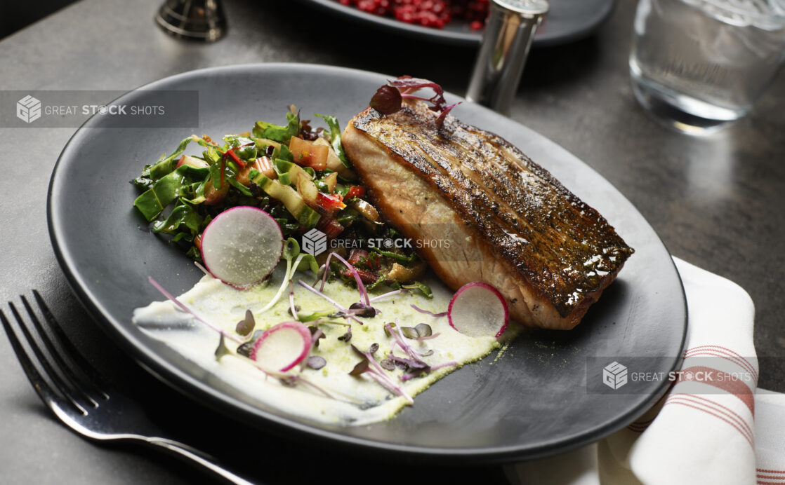 A pan-fried salmon entree with Swiss chard and a puree and microgreen garnish