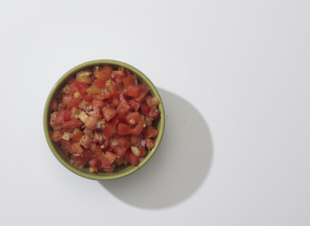 A bowl of bruschetta mix on a white background
