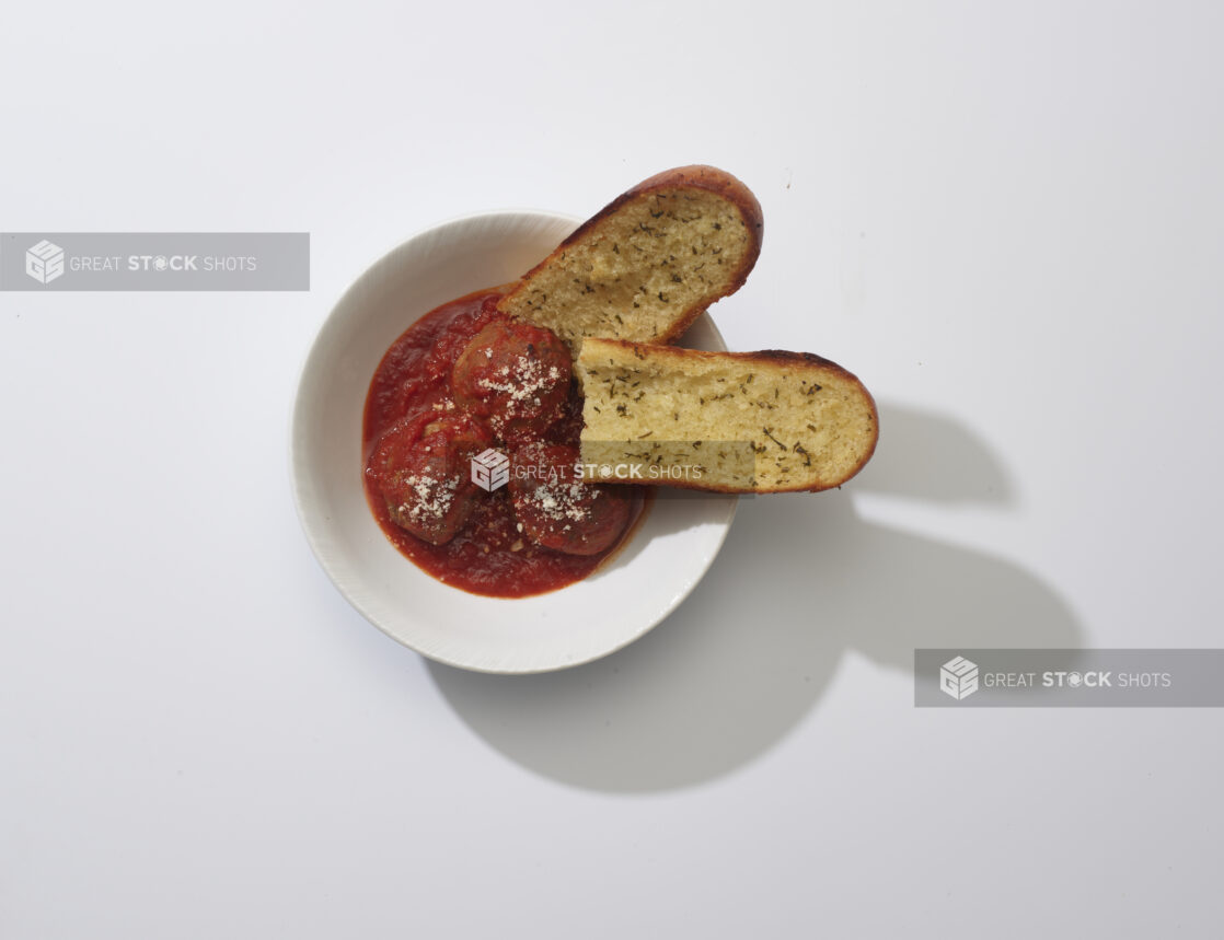 Meatballs and tomato sauce with garlic bread on a white background