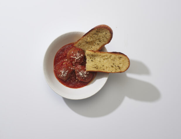 Meatballs and tomato sauce with garlic bread on a white background