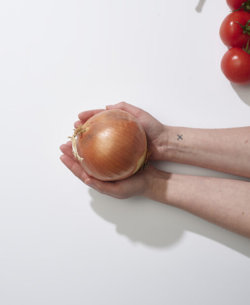 Hands cradling a whole yellow onion